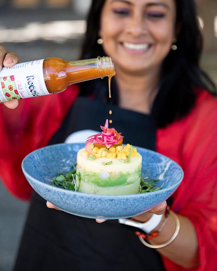Chef Carolina Noble with a Causa and one of her signature hot sauces