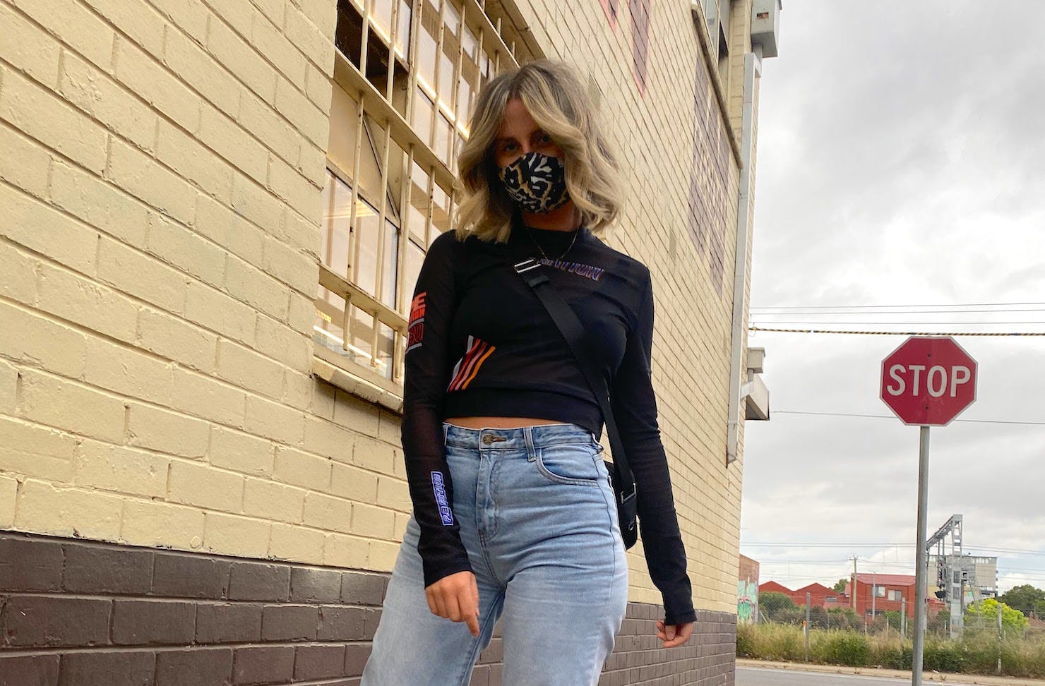 A girl wearing a reusable cloth mask walks down the footpath.
