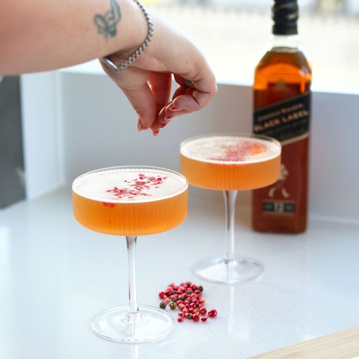 Woman adds garnish to Spiced Brown Derby cocktail made with Johnnie Walker black label