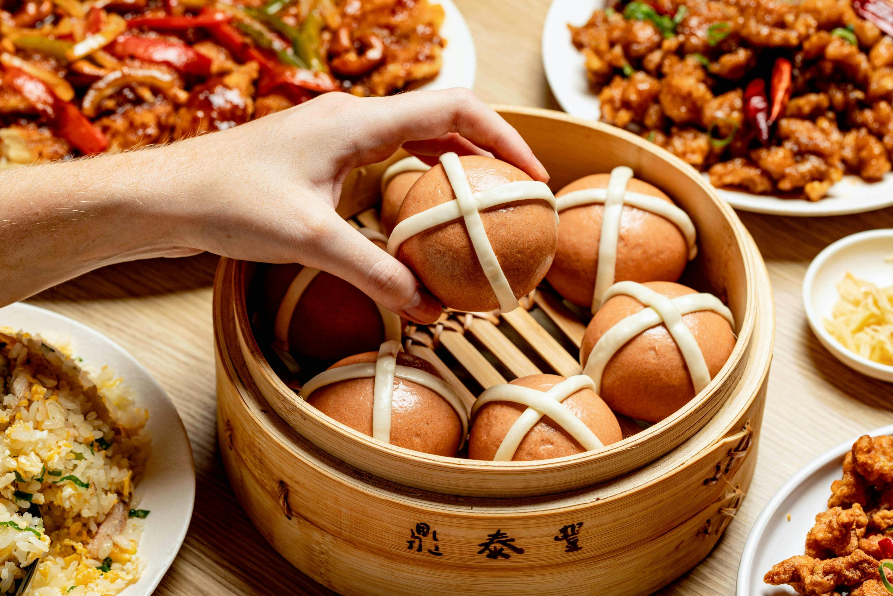 a hand grabbing a hot cross bao