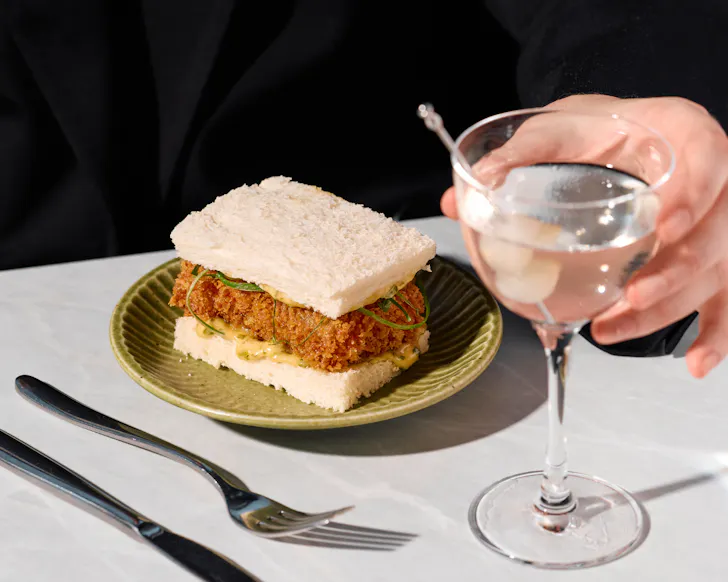 Hand grabbing glass with sandwich