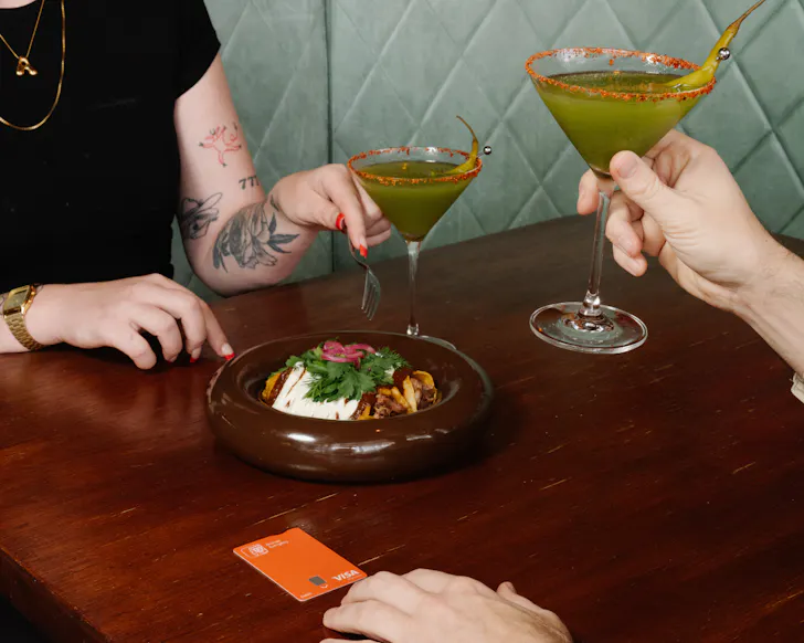 Hands grabbing margarita and bowl of food
