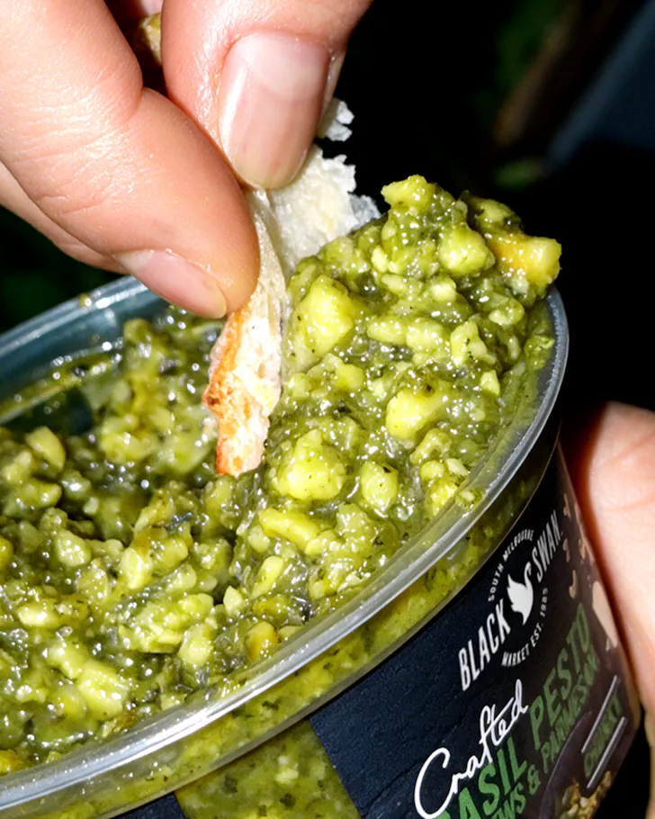 Hand dipping green pesto dip