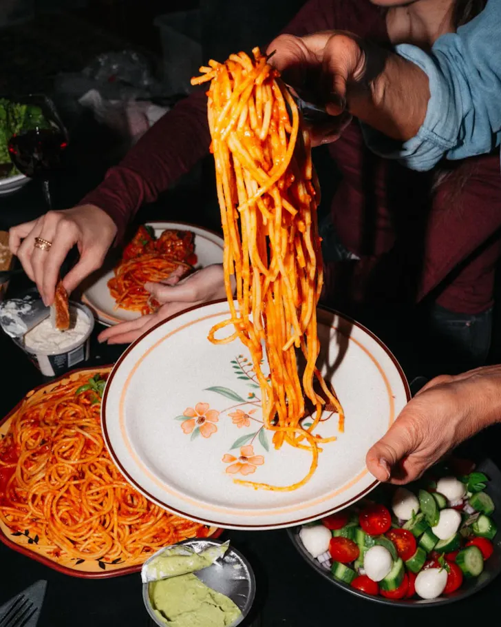 Hand and tongs grabbing spaghetti