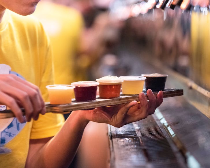 Person holding flight of beers.