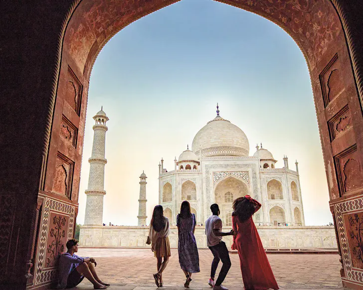 A group of people walk outside the Taj Mahal.