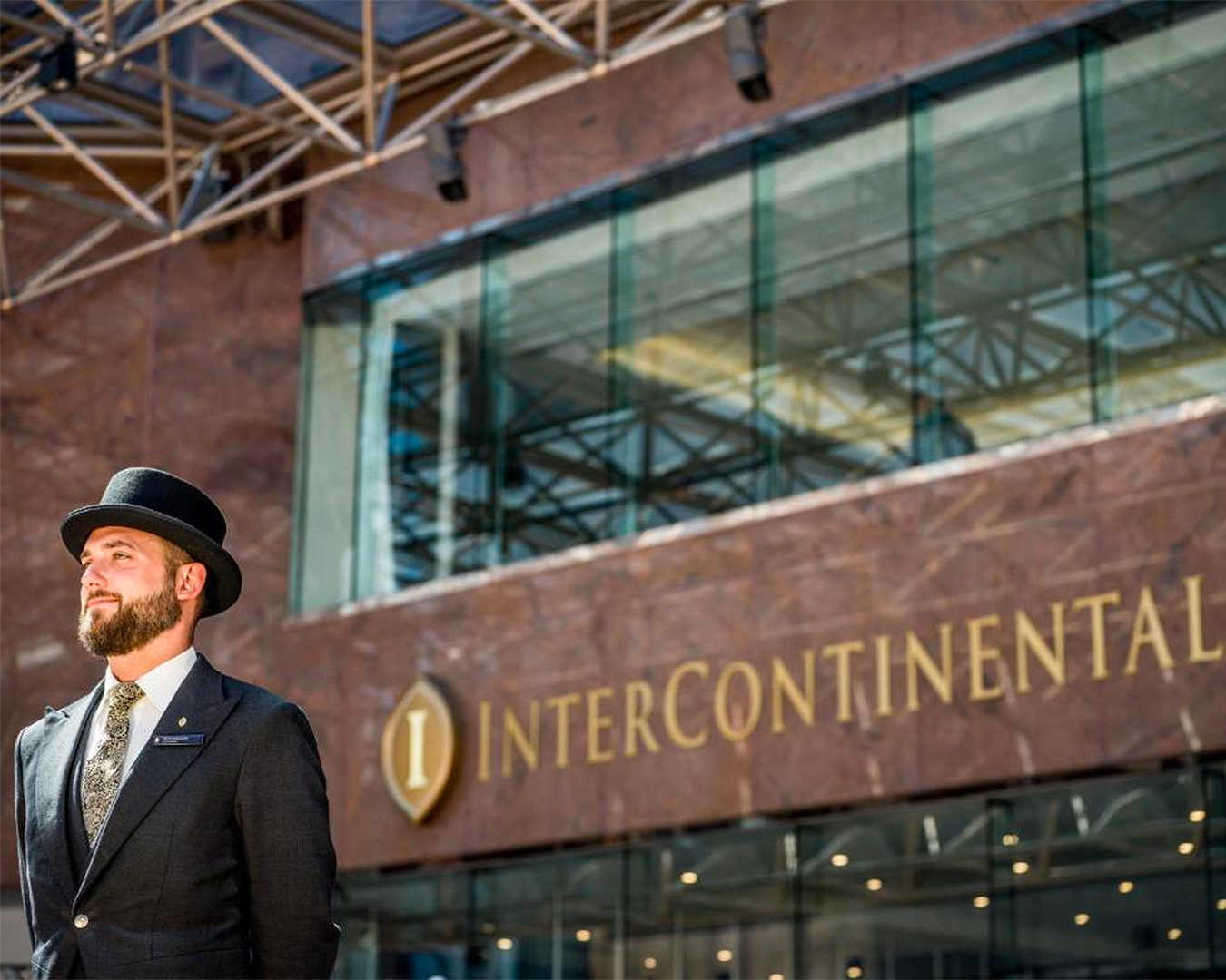 A smartly dressed greeter in a bowler hat stands outside The Intercontinental Hotel in Wellington, waiting to welcome guests.