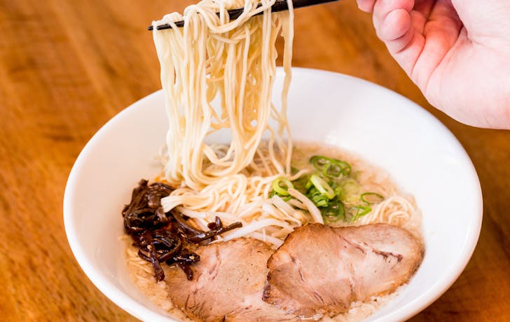 A person holding up noodles from a bowl of ramen at a best Japanese restaurant melbourne.