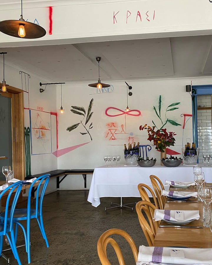 A white-washed interior of a best Lorne restaurant with hanging lights and artwork. 