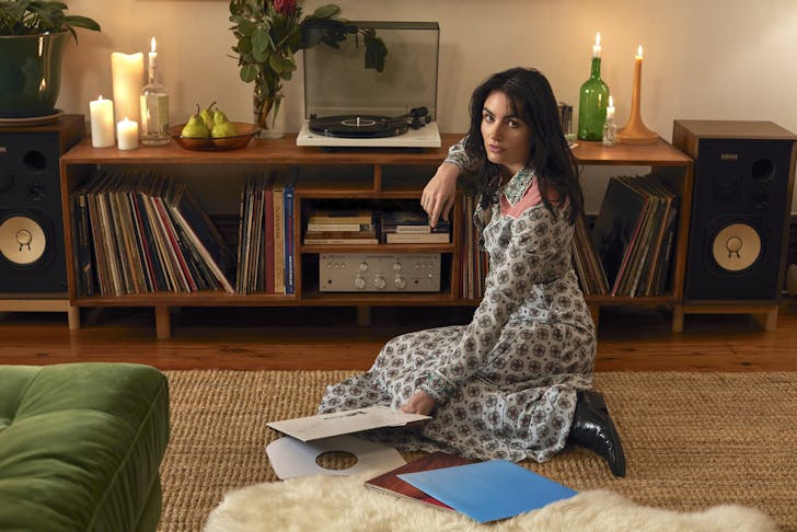 Isabella lounges in her home surrounded by records and candles. 
