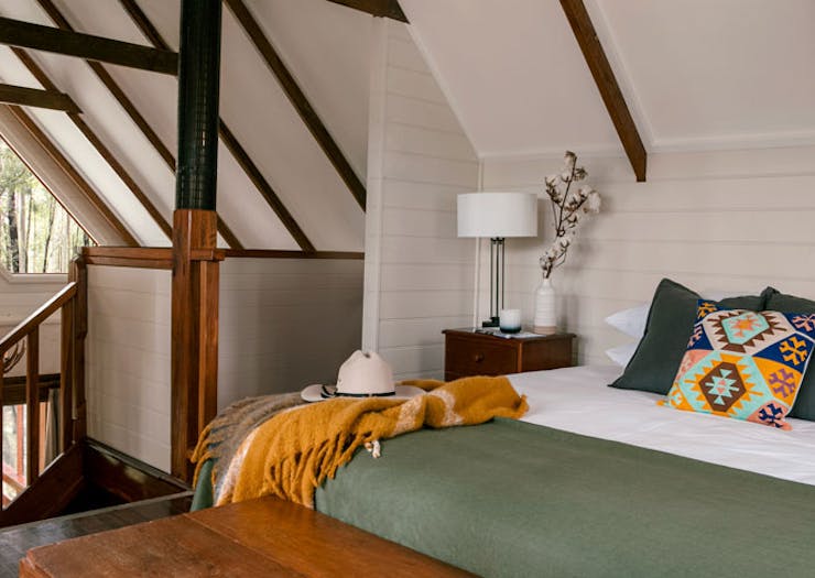 A bedroom with Montana-inspired cushions, and a green duvet.