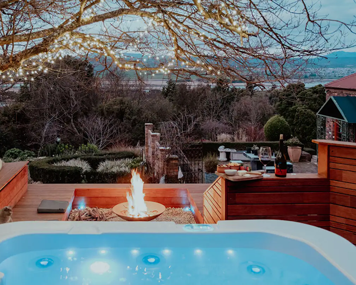 A hot tub overlooks a beautiful lake framed by trees at dusk
