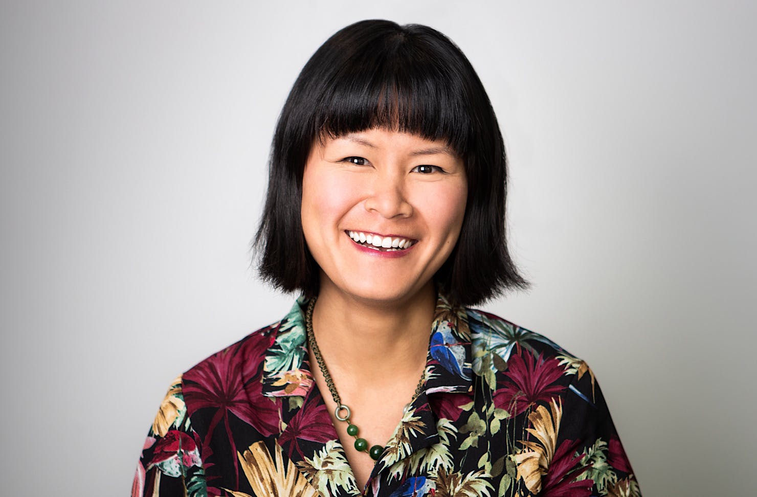 Jade Tang-Taylor smiles wearing a multi-coloured shirt. 