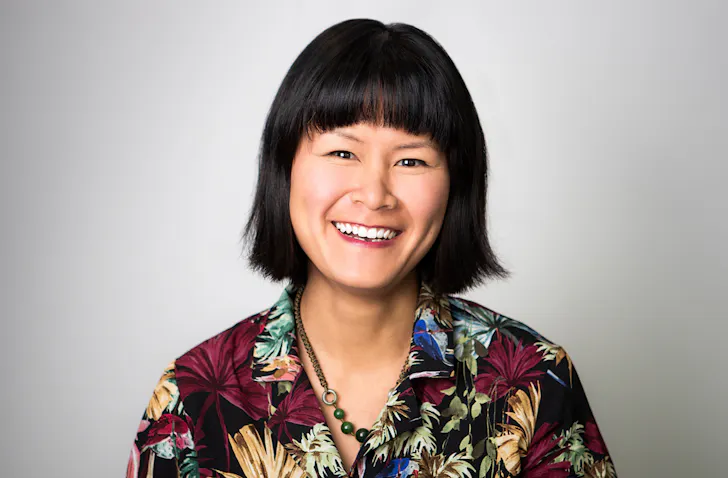 Jade Tang-Taylor smiles wearing a multi-coloured shirt. 