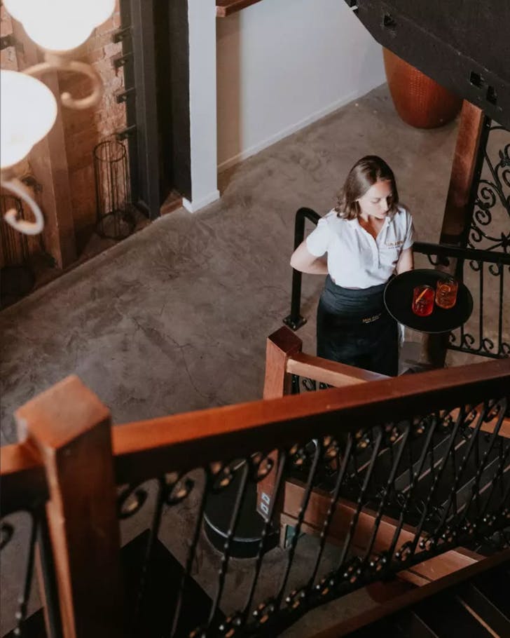 A member of staff at Jais Aben Bar & Bistro heads upstairs with a tray of cocktails. 