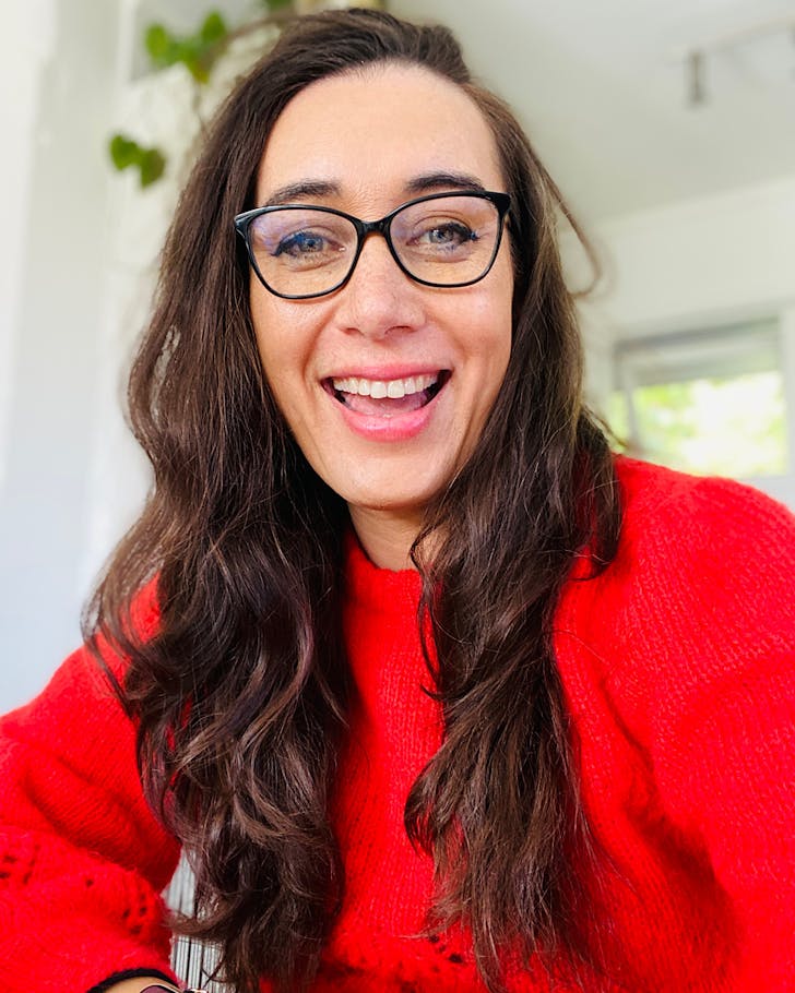 Janina Gaudin wears glasses and a red top and is smiling. 