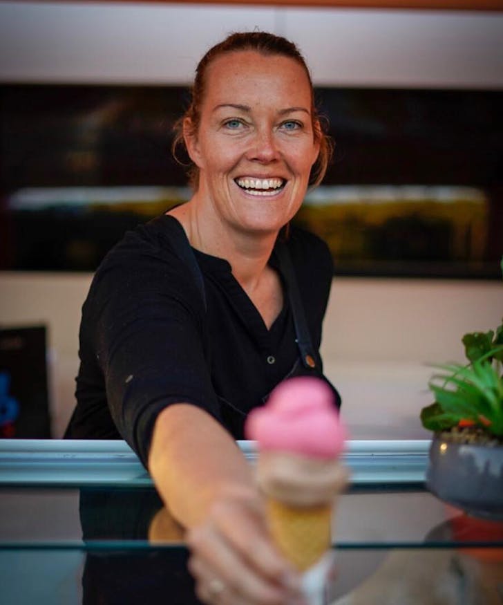 someone handing an ice cream cone over a counter