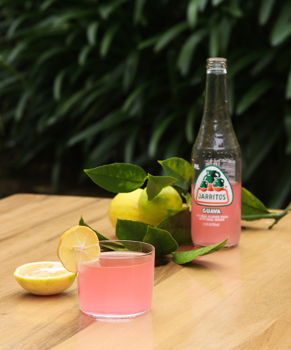 Jarritos Mexican soda sits on a table surrounded by luscious lemons