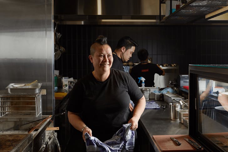 Chef Jerry Mai wearing a black t-shirt smiling in a kitchen.