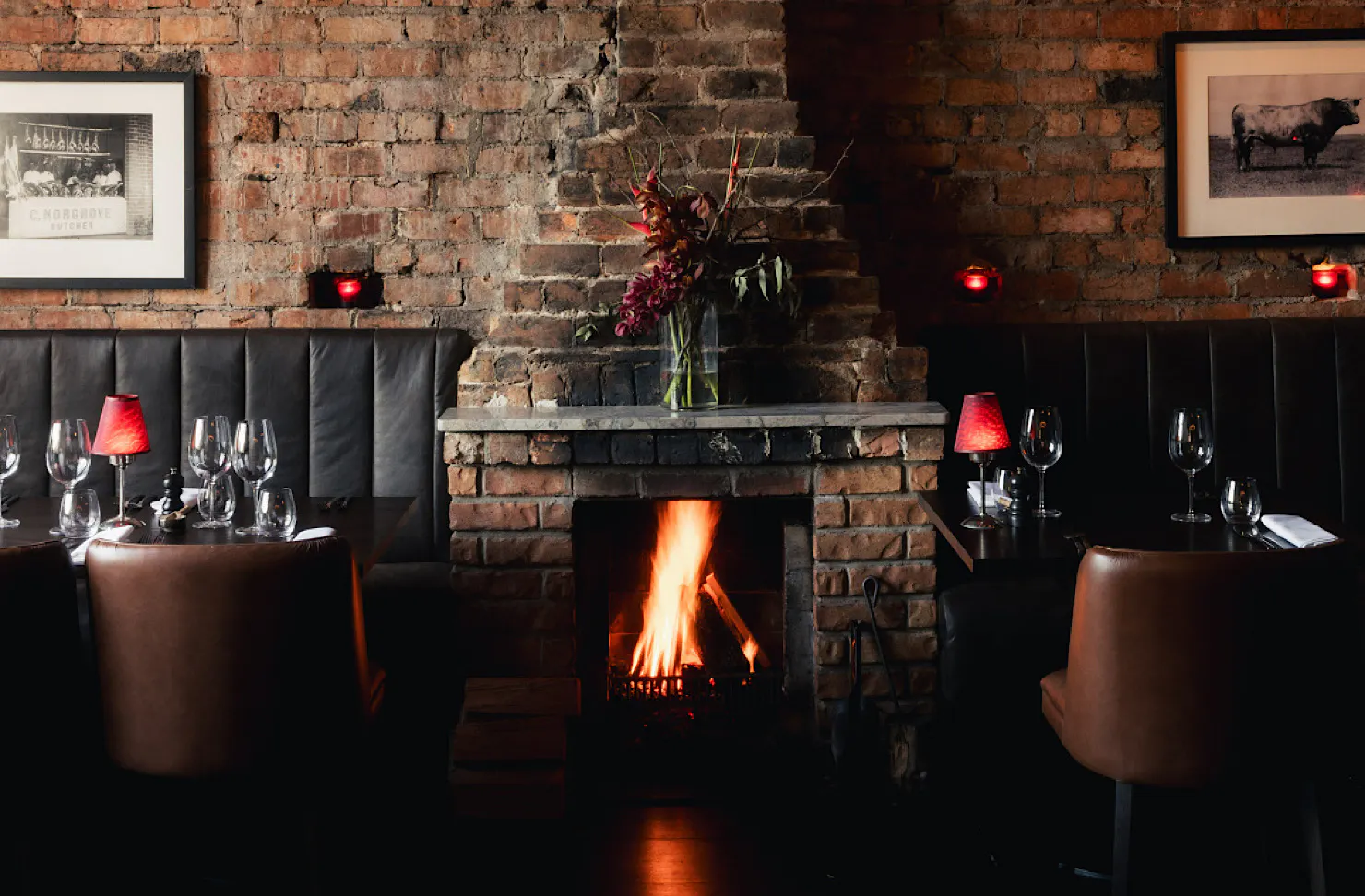 A roaring fire in a chick black, red and brick restaurant interior.