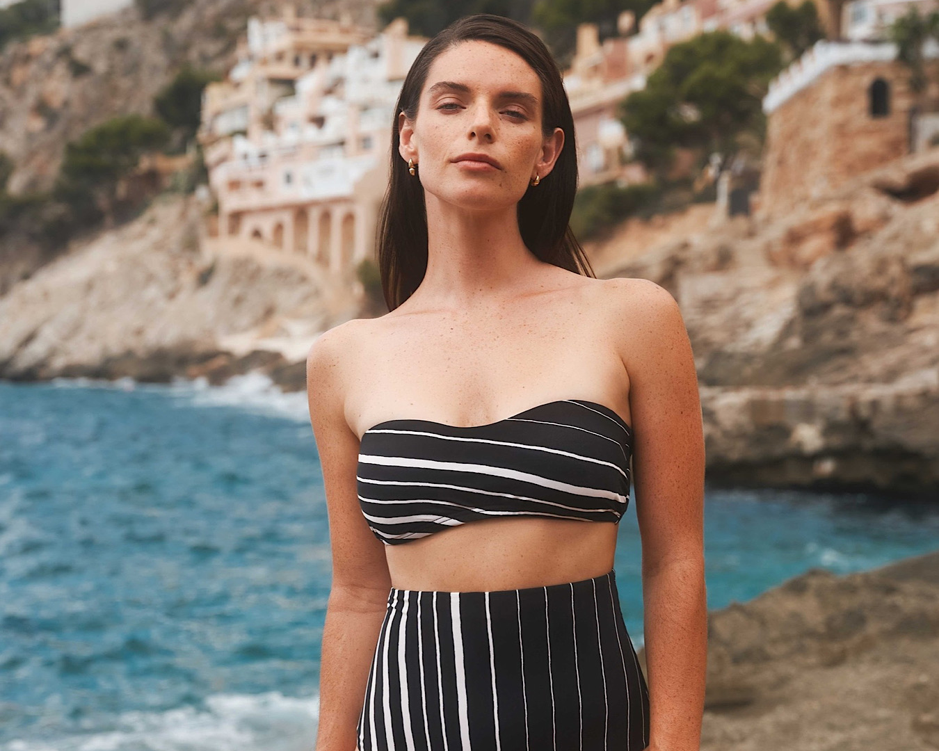 A confident woman wears a black and white striped power bandeau and super high-waisted pant by Jets. 