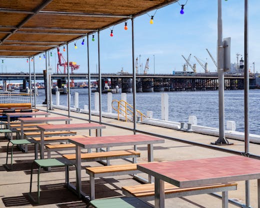 A series of outdoor tables by the water.