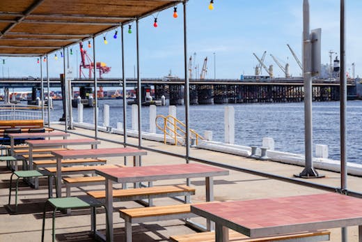 A series of outdoor tables by the water.