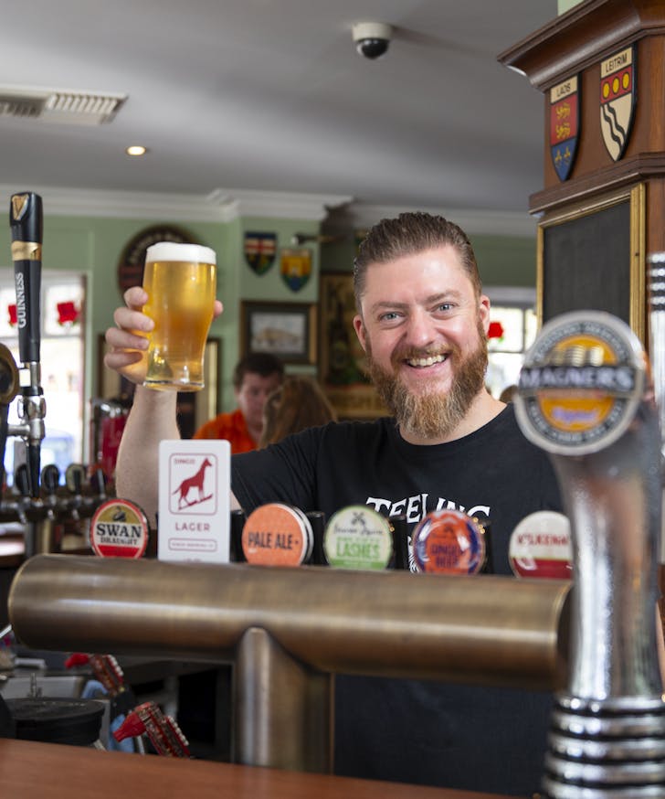 Paul Maloney holding beer behind the bar at Johnny Fox's
