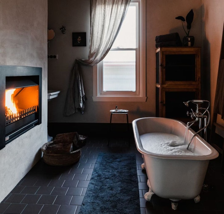 The white claw foot bath next to the fireplace at Jon Jon Airbnb Victoria