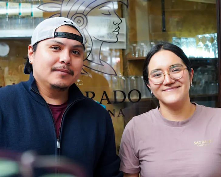 Andrea and Jorge stand together outside Sagrado Cantina, smiling. 