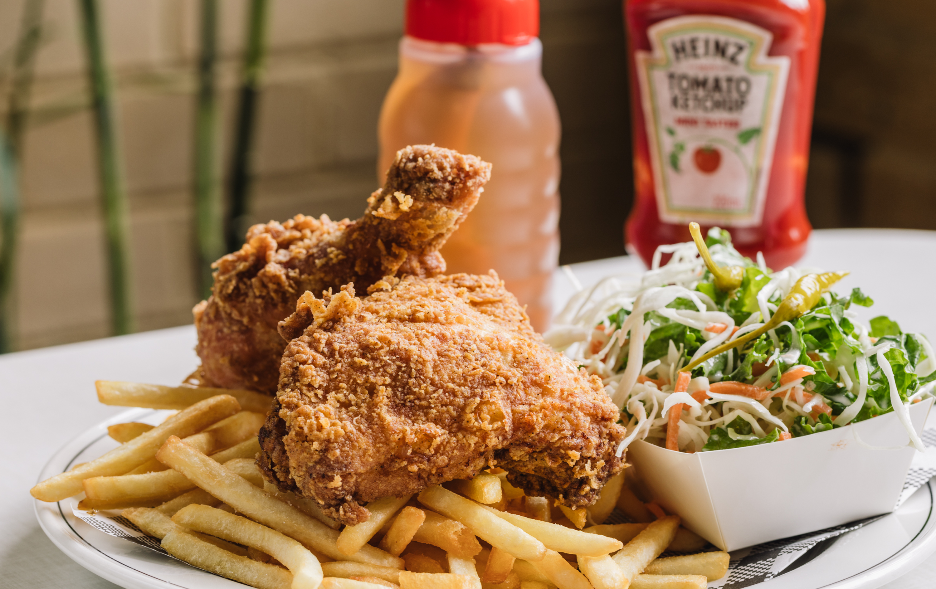 Two pieces of the best fried chicken on top of a plate of fries. 