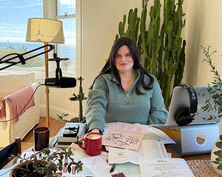 Julie sits at her desk surrounded by menus, ready to record a new episode of Pizza Pepperoni Dreams. 