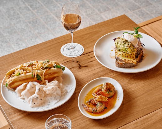 A table will different dishes and a glass of wine. 