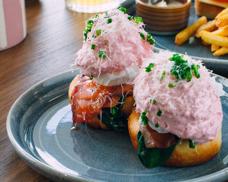 Two bacon eggs bene muffins topped with fluffy, candyfloss-coloured hollandaise. 
