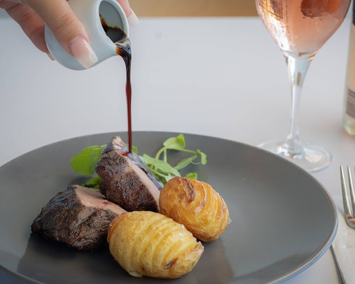 Gravy being poured over steak