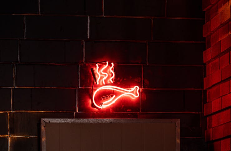 A neon drumstick sign sits above a refrigerator door.