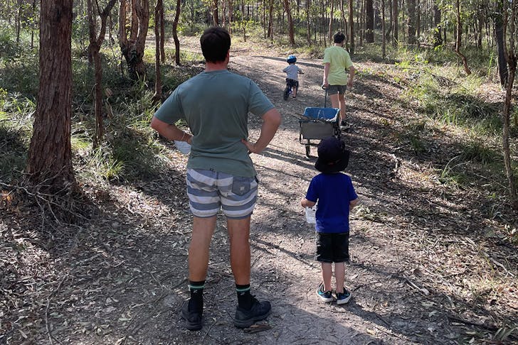 a dad and three kids walking through bushland