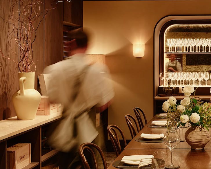 A blurred silhouette of someone in a chic private dining room.