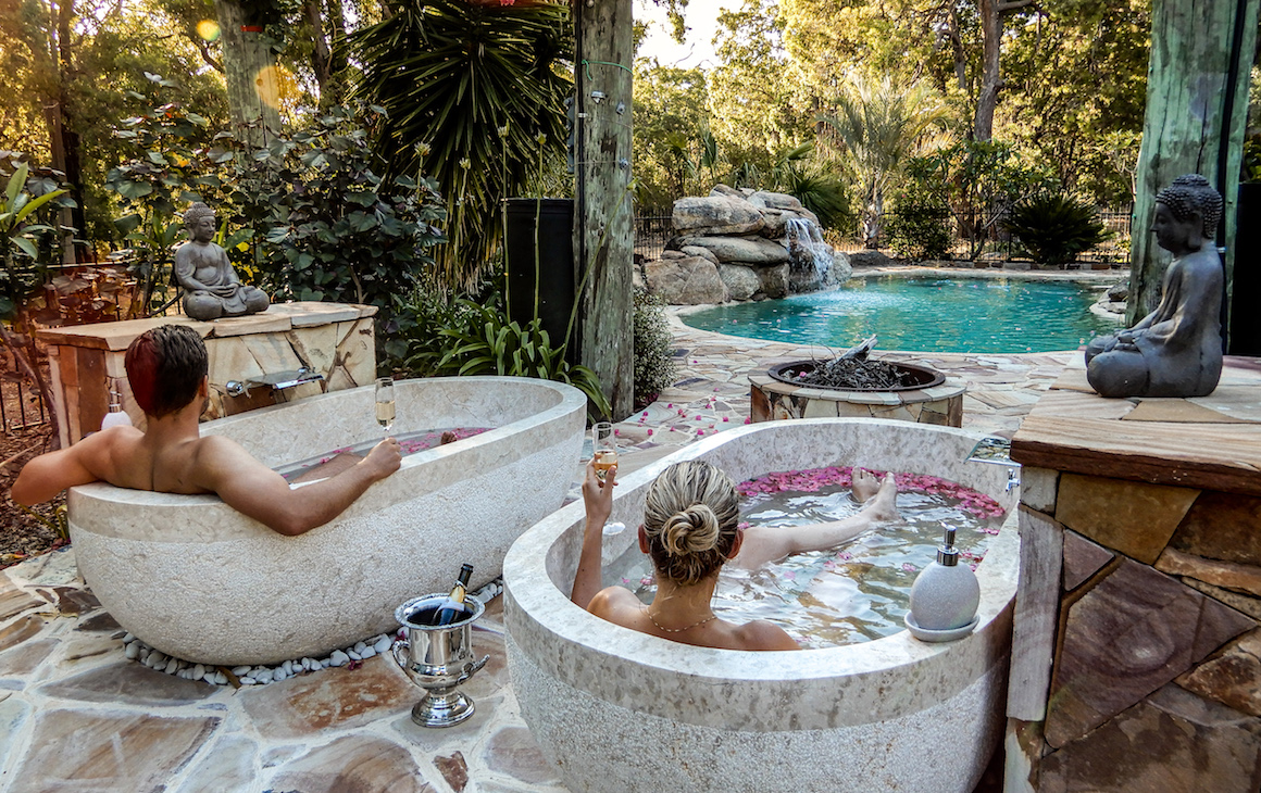 Two people relaxing in outdoor tubs