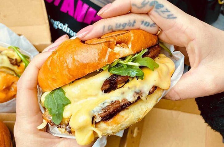 A stacked burger with cheese oozing out of it. 