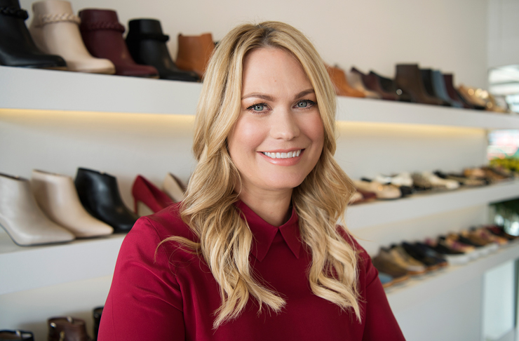 Kathryn Wilson sits in front of shelves of shoes she designed
