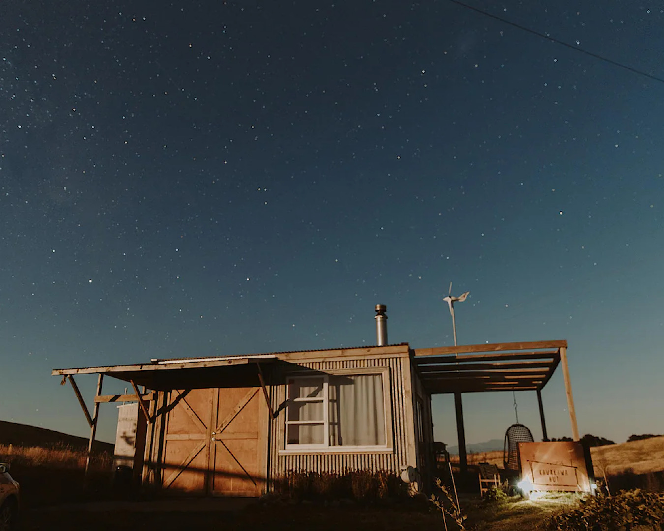 A gorgeous wooden hut sitting beneath a starry night sky. 