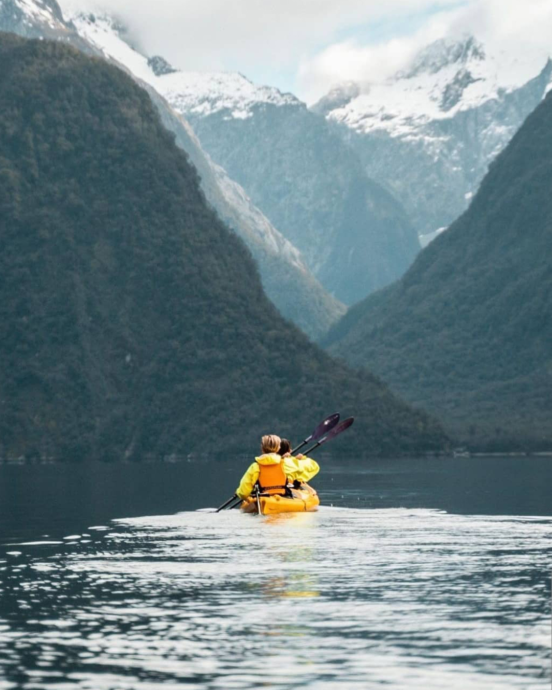 Back view of a person kayaking through Milford Sound