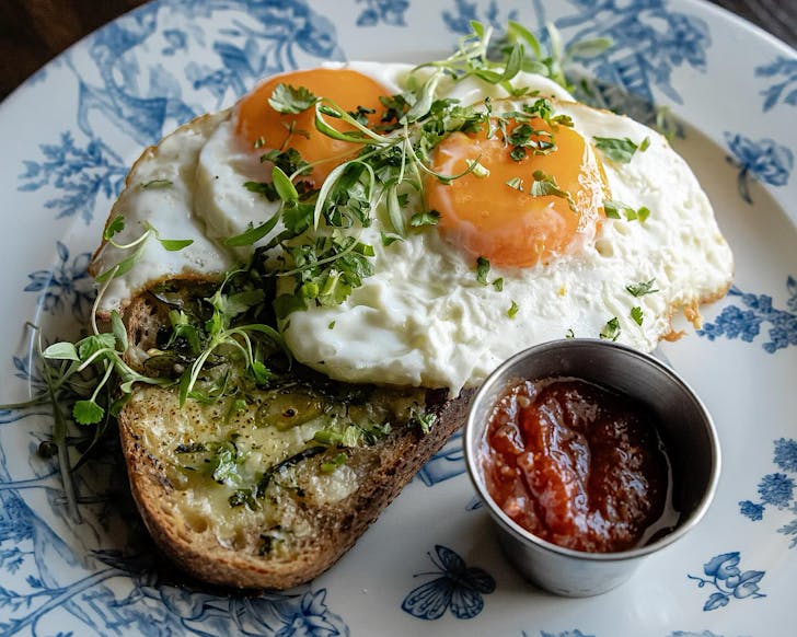 Sunny side up eggs on chilli cheese toast on a blue china plate.