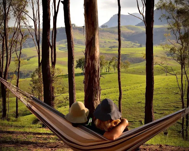 Two people in a hammock with a mountain view at Ketchup’s Bank Glamping one of the best romantic getaways near Gold Coast
