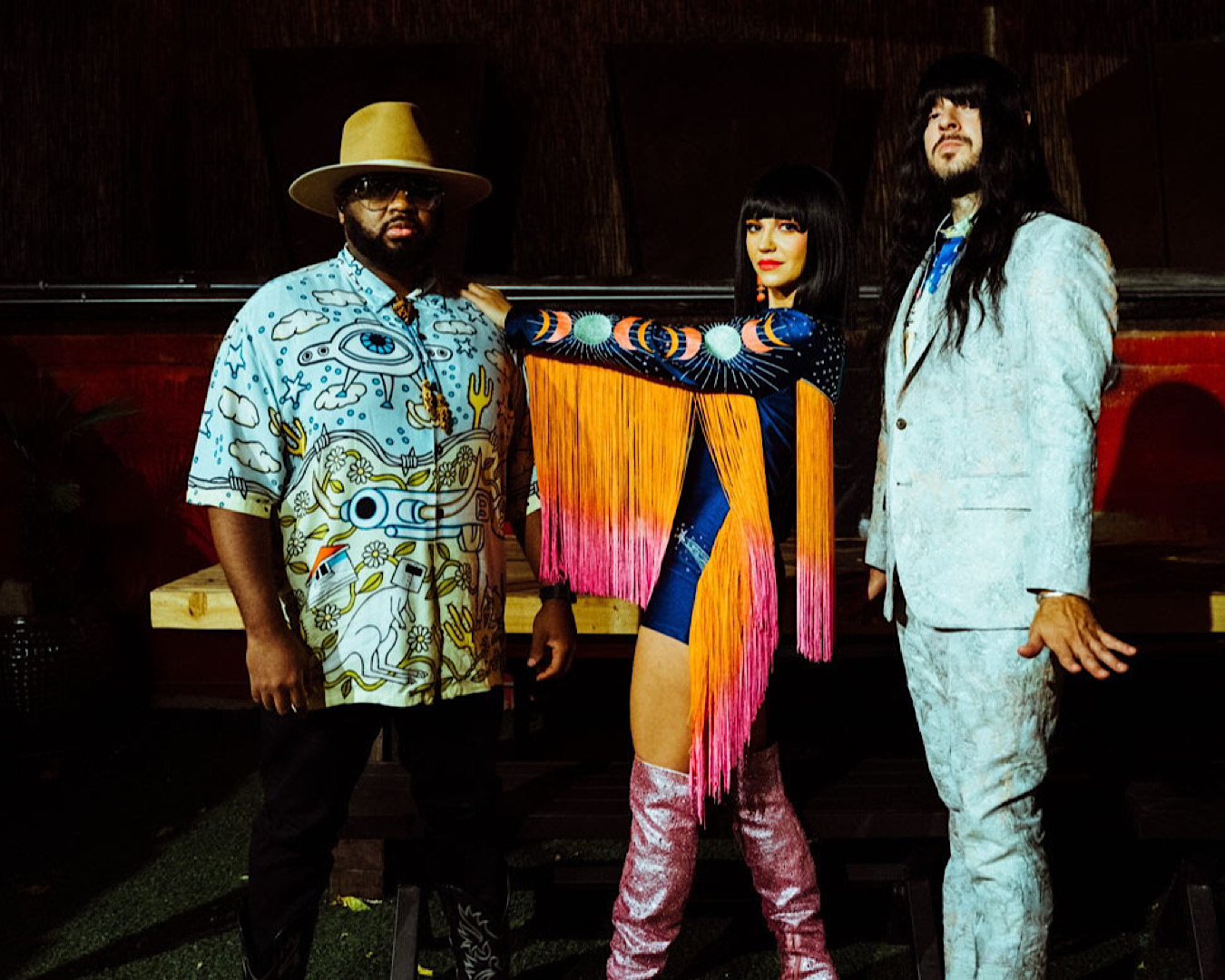 The three members of Khruangbin pose together in epic outfits exuding cool.  