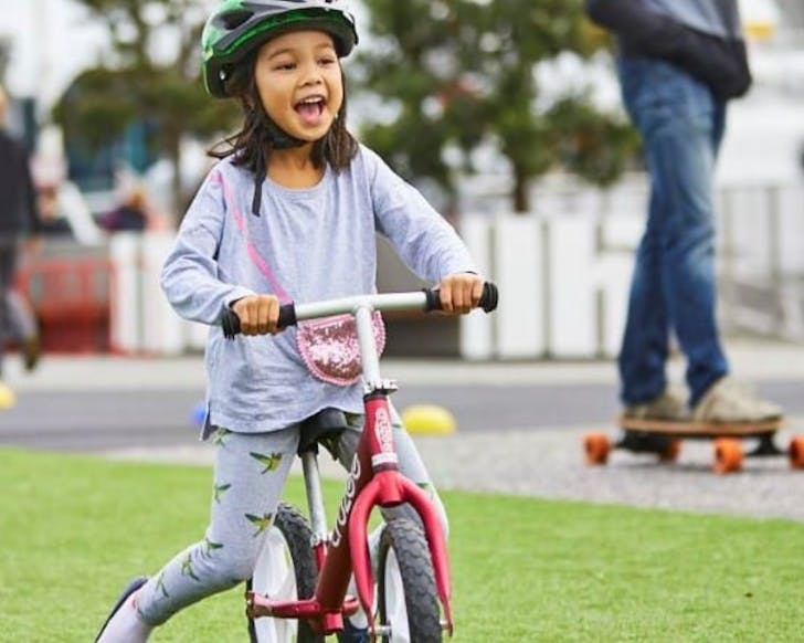A child is all smiles at the Kids Learn To Ride Wynyard Quarter event, one of the best Auckland kids' activities in May. 