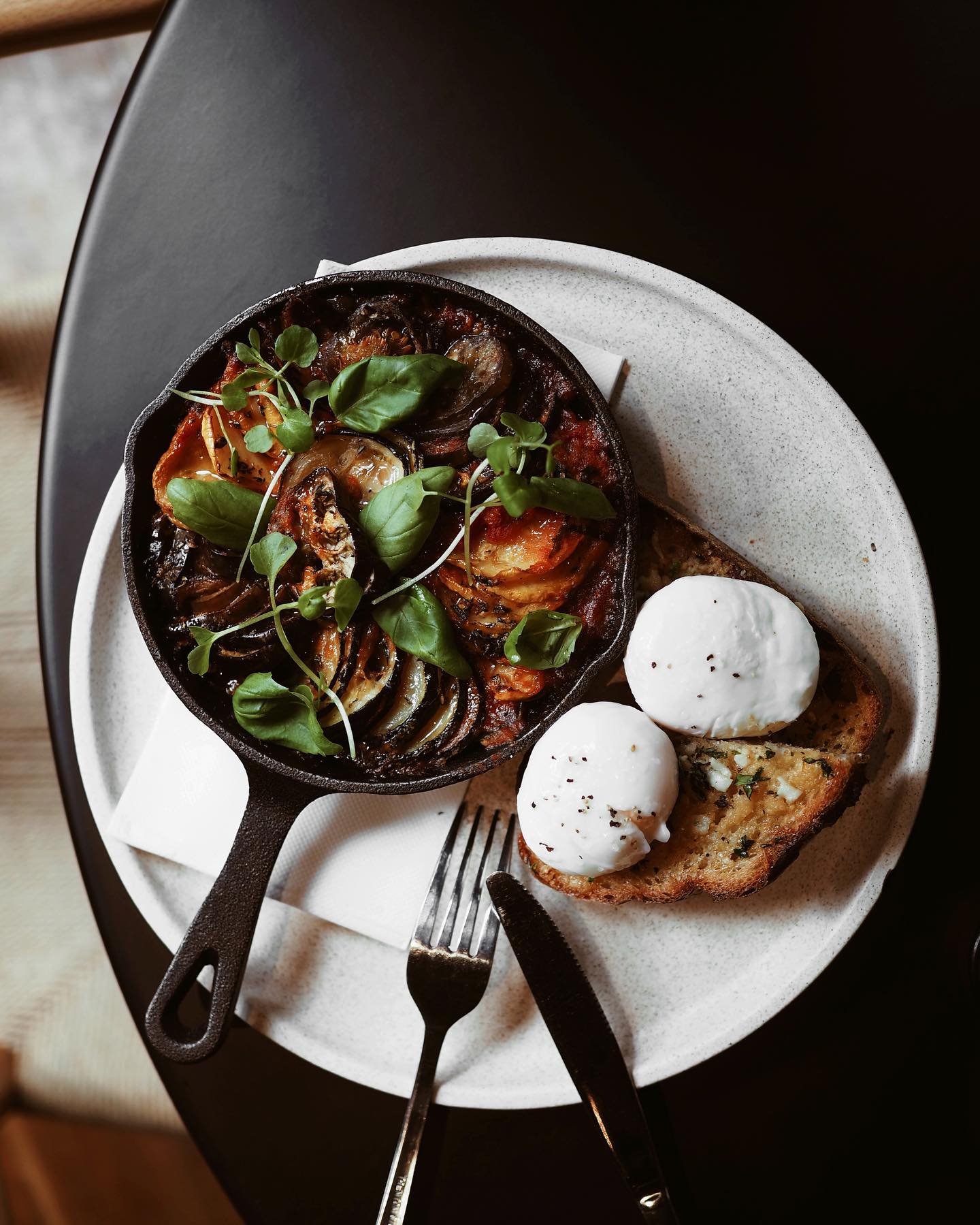 baked vegetable dish with poached eggs and rye bread