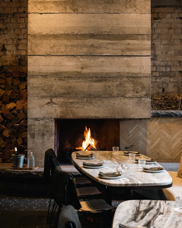 A neutral-toned dining setting, with a fireplace. 
