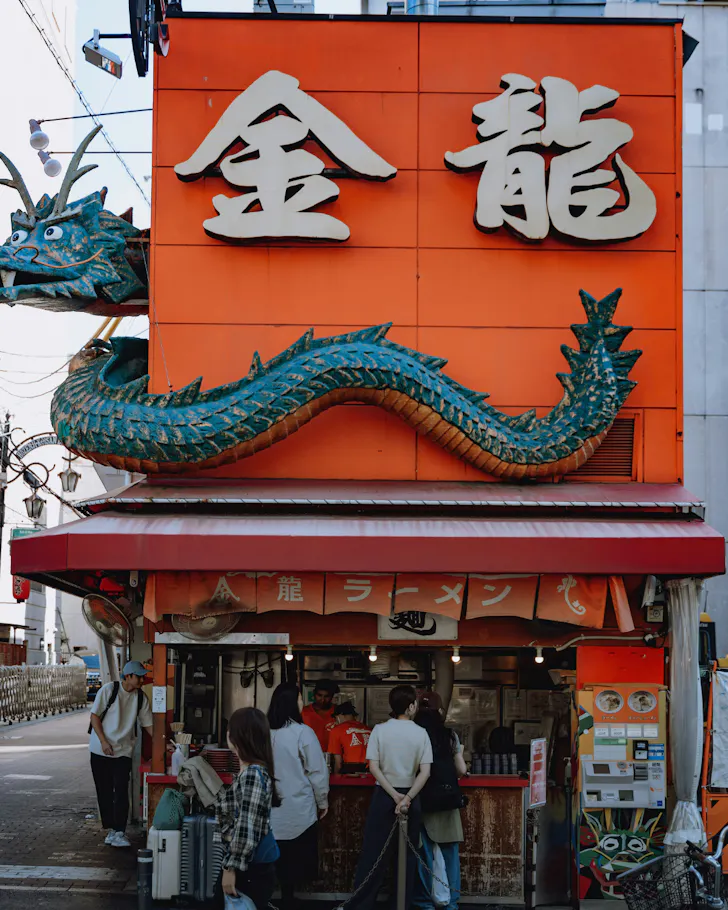 A cartoon dragon wraps around the red building of Kinryu Ramen in Osaka. 